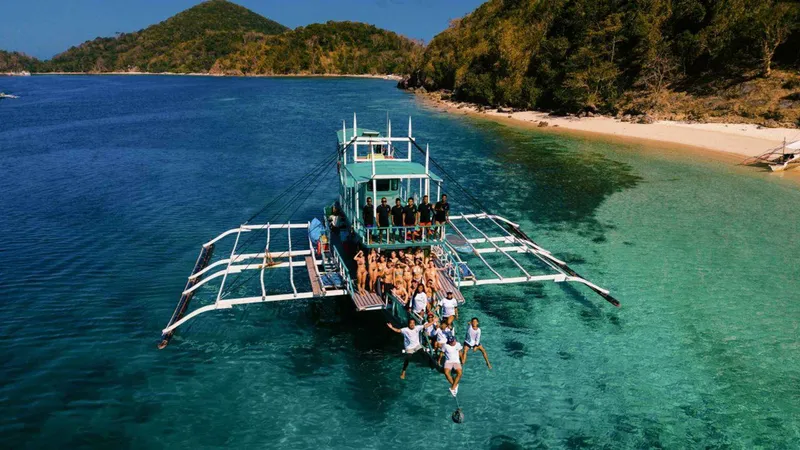 Travellers snorkelling over shallow reef from an expedition bangka on a 3-day El Nido to Coron island hopping tour, Palawan, Philippines